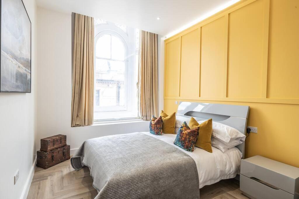 a bedroom with a bed with yellow walls and a window at The Pocklington - The Bradgate Suite in Leicester