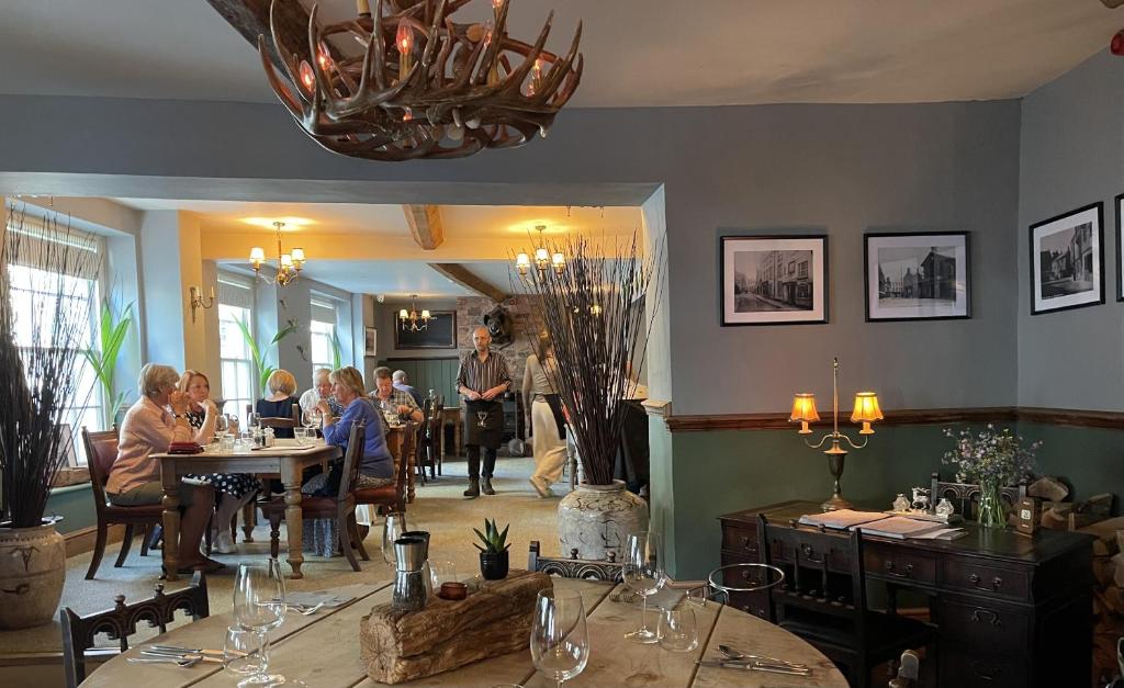 un grupo de personas sentadas en mesas en un restaurante en White Hart Hotel en Wiveliscombe