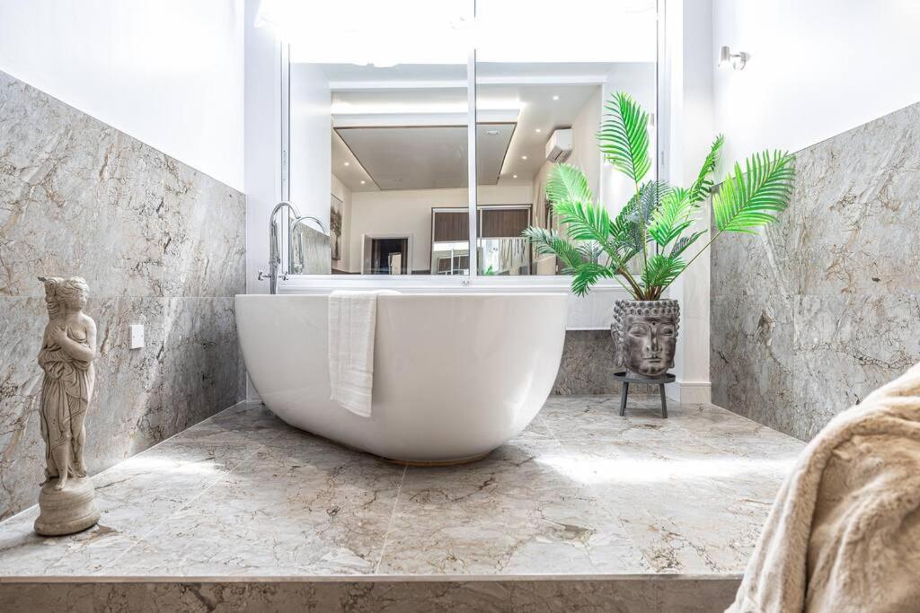 a large white tub in a bathroom with a plant at The Pocklington - The Ceremonial Suite in Leicester