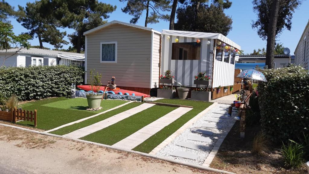 a backyard with a house with a grass yard at MH 127 Bois Dormant 3ch climatisé in Saint-Jean-de-Monts