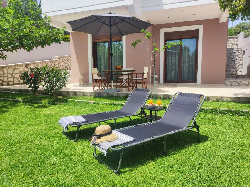 two chairs and a table and an umbrella in a yard at Rhodes Soul Iuxury home in Asgourou