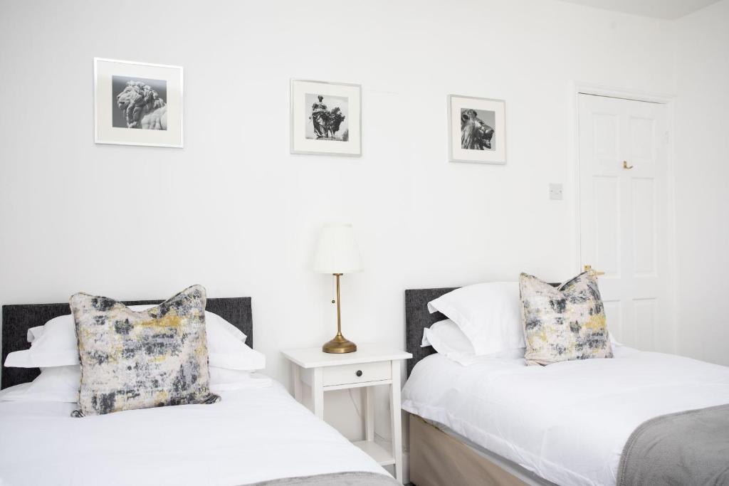two beds in a room with white walls at 30 Percent Off Monthly Stays - City Centre - 3 Bedrooms in St. Albans