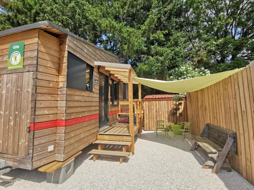 uma cabina de madeira com uma tenda e um banco em La Charmotte, tiny House insolite 