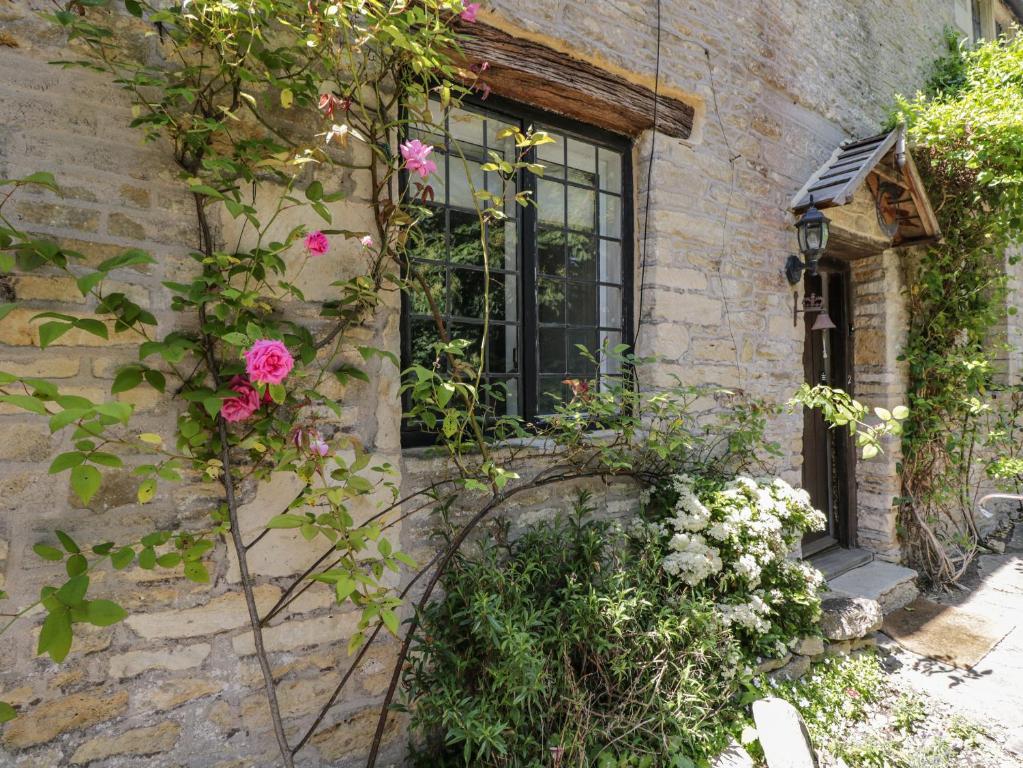 a window with flowers on the side of a building at Fox Den Cottage in Castle Combe