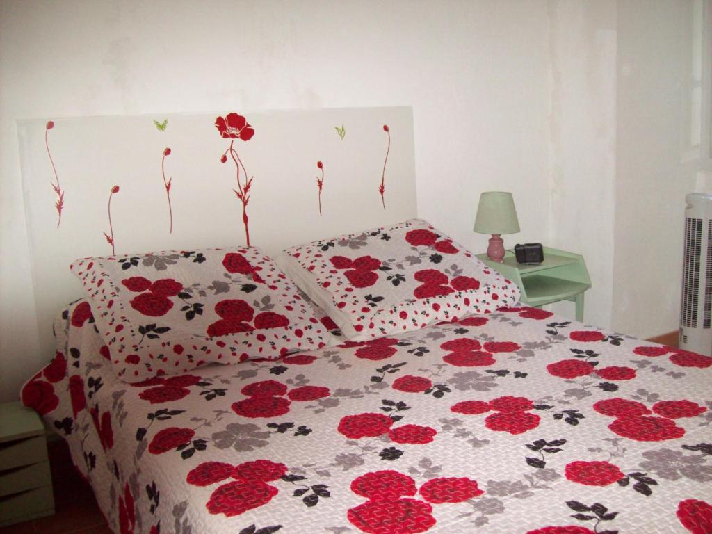 une chambre avec un lit avec des fleurs rouges dessus dans l'établissement LA CORSE la montagne, les plages, les iles, à Monticello