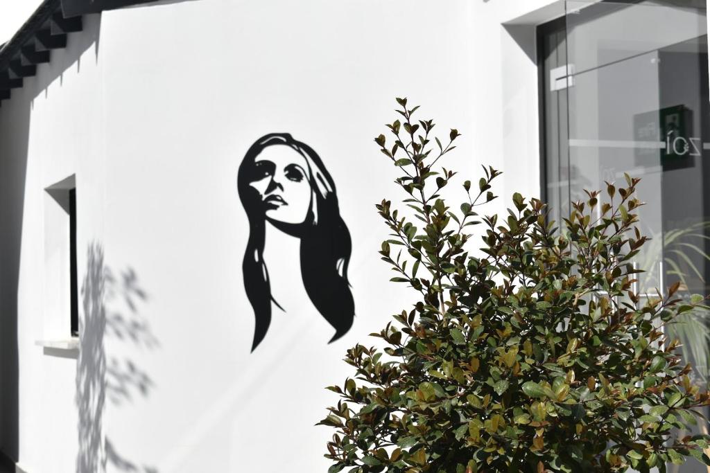 a mural of a woman on a wall next to a plant at Zoi Ayia Napa in Ayia Napa