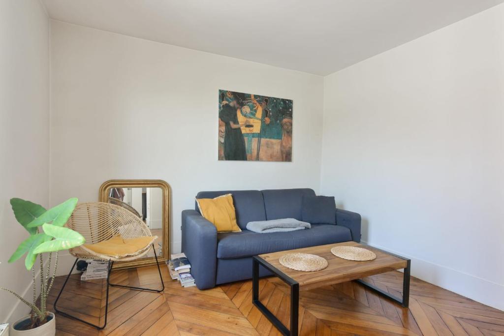 a living room with a blue couch and a table at Charming flat in the heart of the 14th district of Paris - Welkeys in Paris