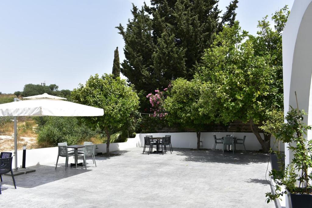 a patio with tables and chairs and an umbrella at Zoi Ayia Napa in Ayia Napa