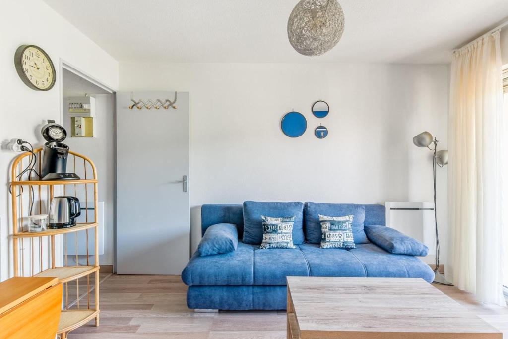 ein Wohnzimmer mit einem blauen Sofa und einem Tisch in der Unterkunft Charming 1br with sunny balcony - Houlgate - Welkeys in Houlgate