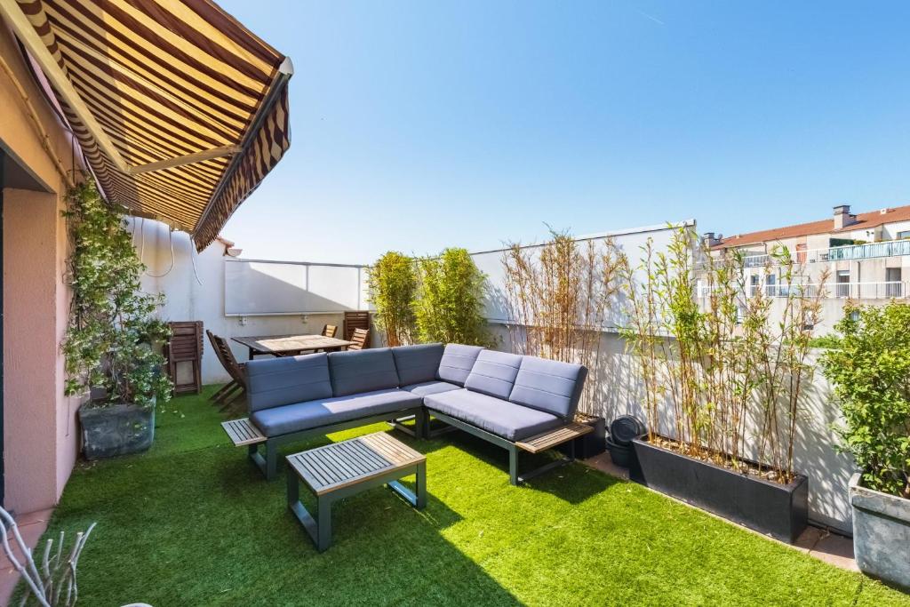 un patio d'appartement avec un canapé et de l'herbe dans l'établissement Appartement Gaston - Welkeys, à Marseille