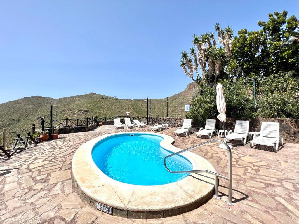 a swimming pool with lounge chairs and an umbrella at Apto en una casa rural, con cocina, piscina, barbacoa compartidas y vistas en Sur de Tenerife in San Miguel de Abona
