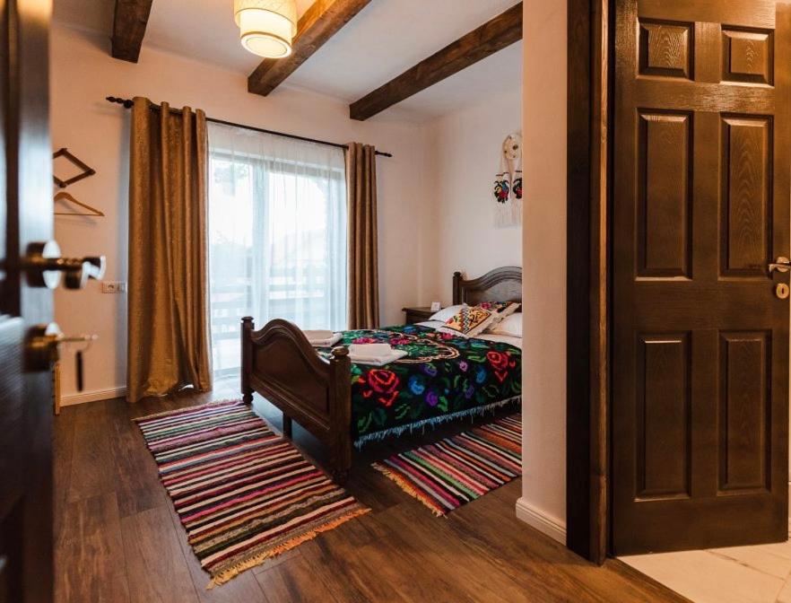 Schlafzimmer mit einem Bett, einem Fenster und einer Tür in der Unterkunft Conacul maramureșean Bilgăr in Bogdan Vodă