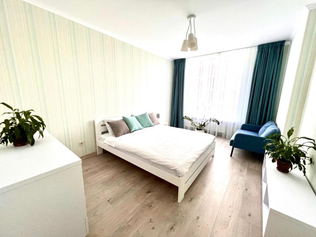 - une chambre blanche avec un lit et une chaise bleue dans l'établissement Cozy apartment in a complex Semycvit, à Lviv