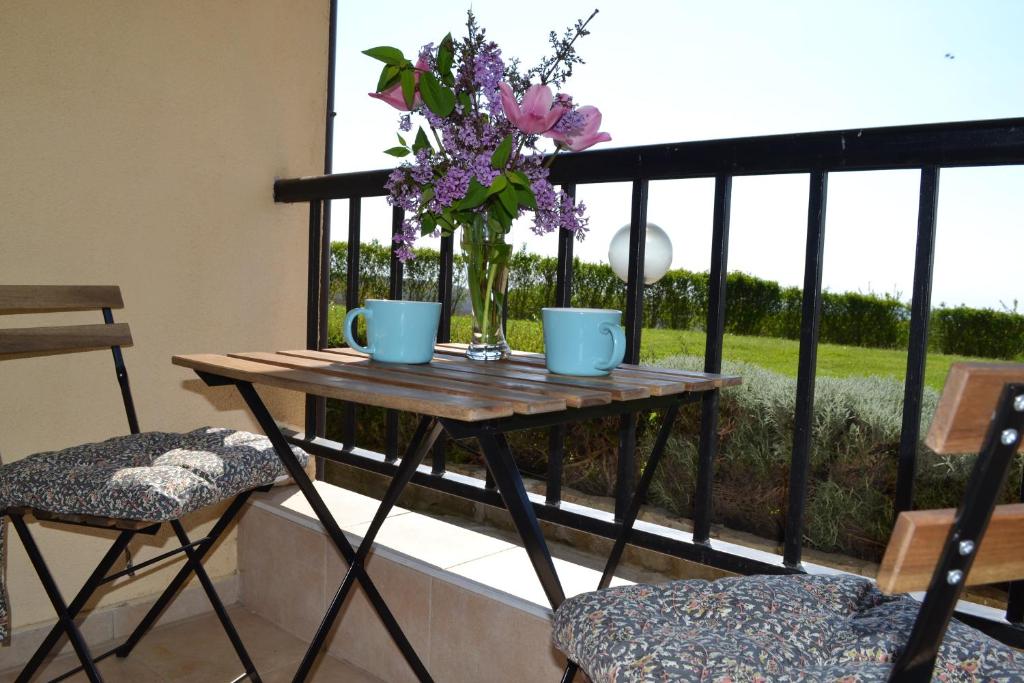 una mesa con un jarrón de flores en el balcón en Апартамент в Oasis beach Kamchia - Стъпки в пясъка, en Kamchia