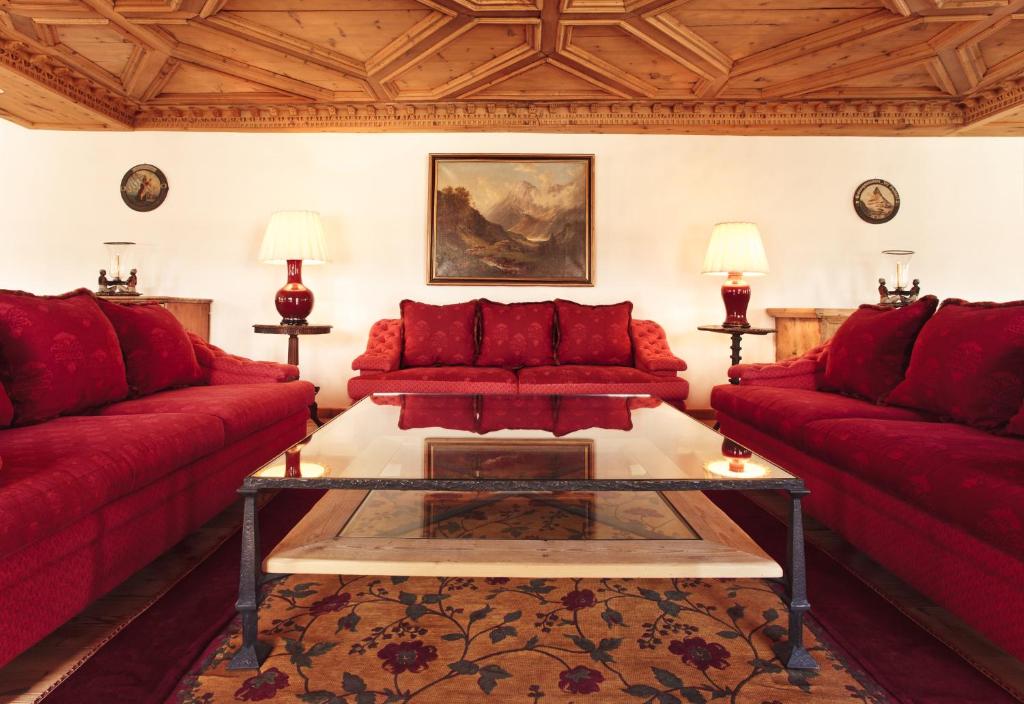 a living room with red couches and a table at Top of the World Apartment in St. Moritz
