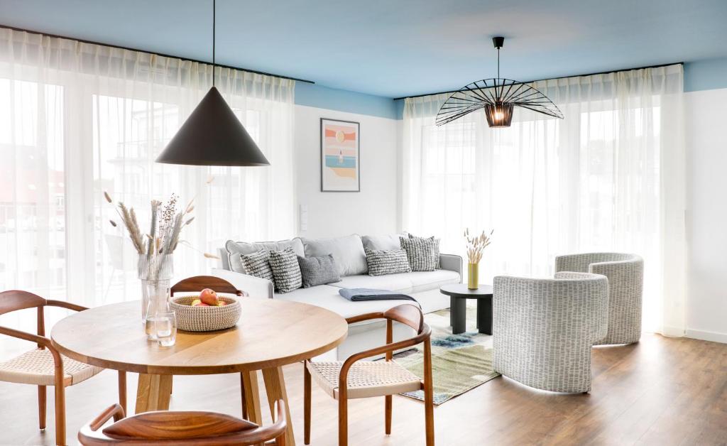 Seehuus Duhnen Apartments في كوكسهافن: غرفة معيشة مع أريكة وطاولة وكراسي