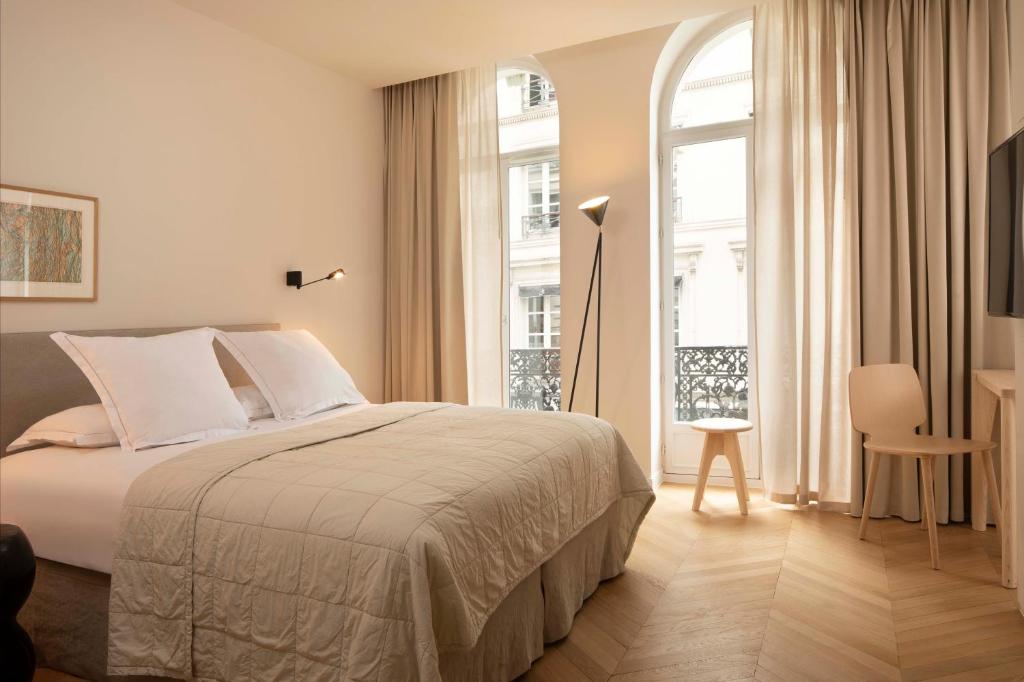 Résidence Nell Paris في باريس: غرفة نوم بسرير ونافذة كبيرة