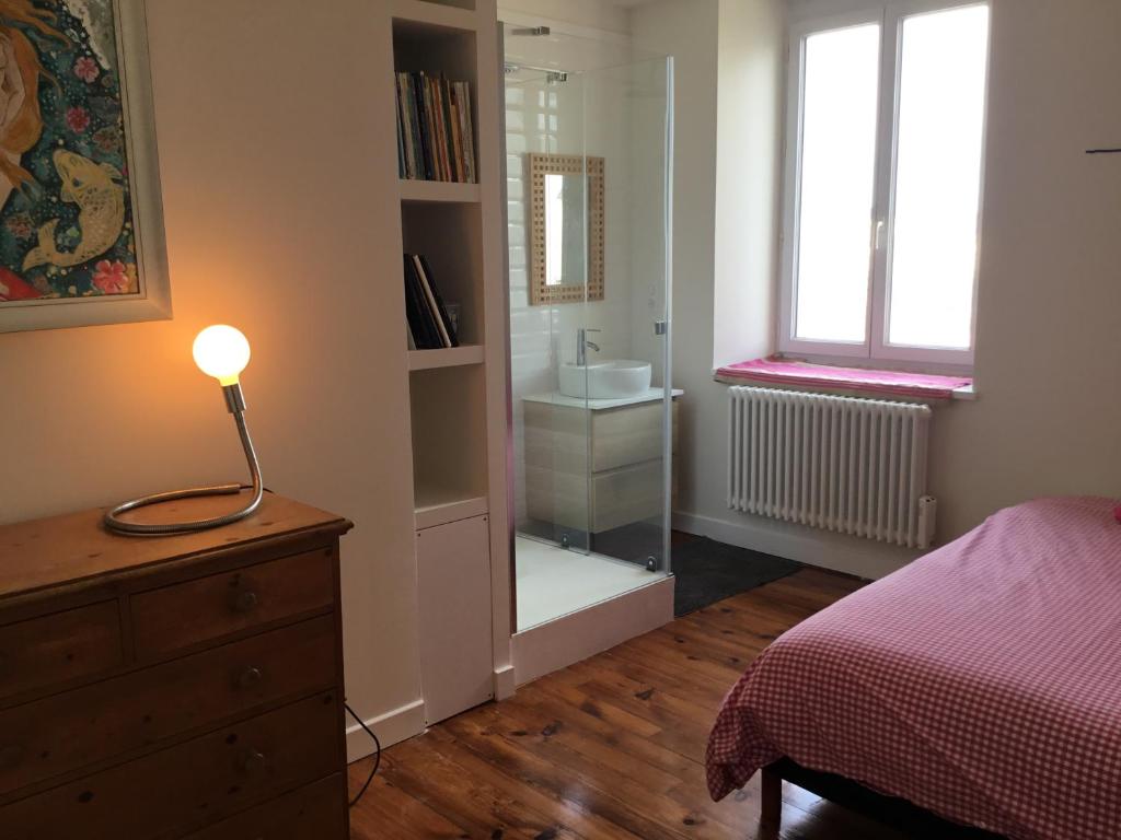 een slaapkamer met een bed en een lamp op een dressoir bij Loft en duplex avec terrasse Halles in Biarritz