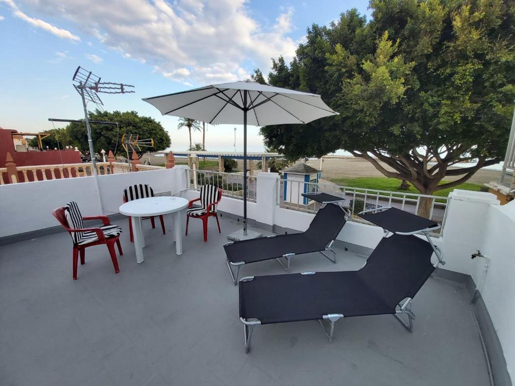 a patio with a table and chairs and an umbrella at BeachFront House in Málaga