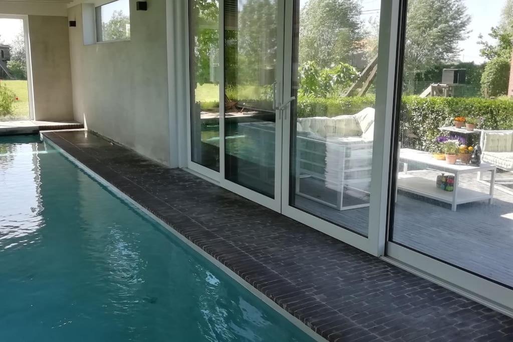 a swimming pool next to a house with glass doors at Dreve 14 - bovenverdieping in Staden