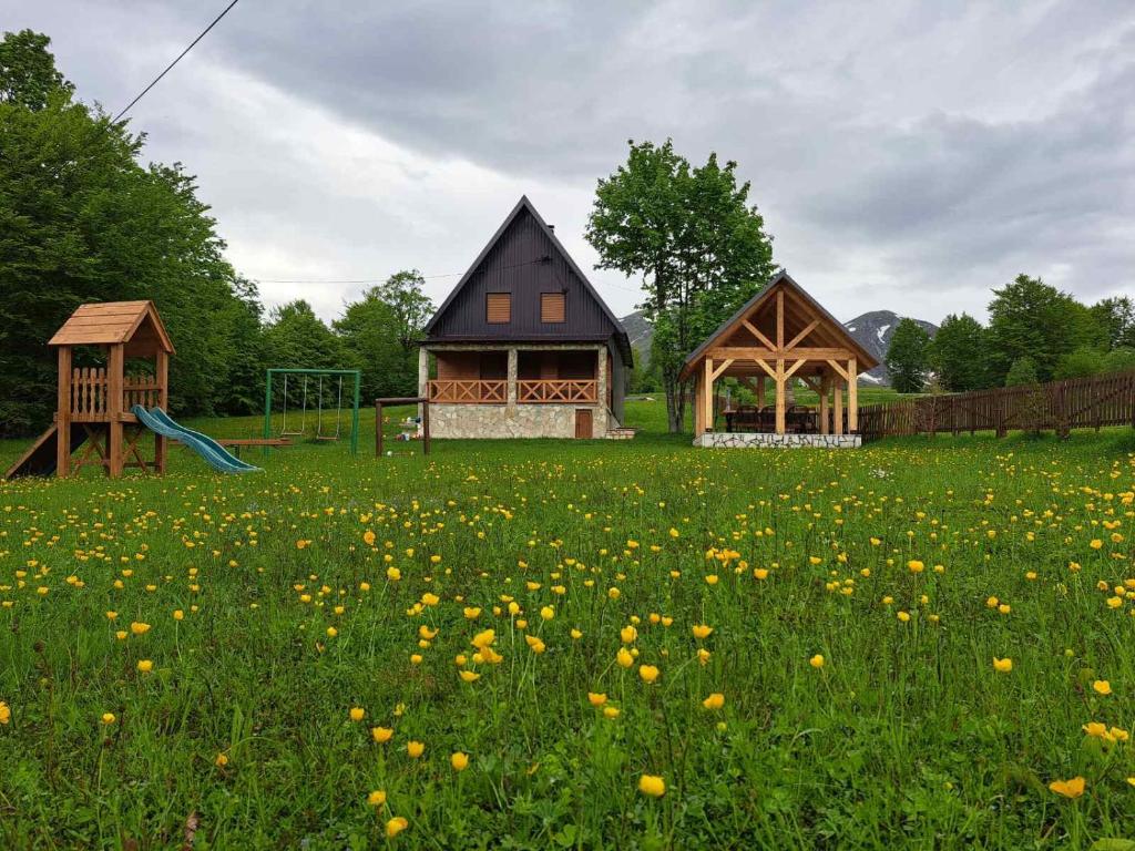 una casa y un parque infantil en un campo de flores en Vila Durmitor Nest Krstajic en Žabljak