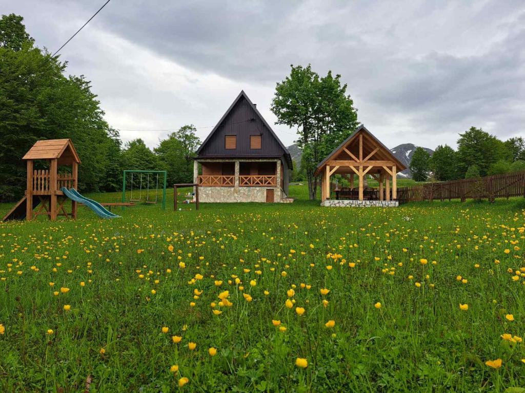 une maison et une aire de jeux dans un champ de fleurs dans l'établissement Vila Durmitor Nest Krstajic, à Žabljak