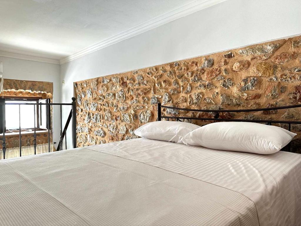 1 dormitorio con 1 cama grande y pared de piedra en Lovinna Luxury Appartments, en Kalymnos