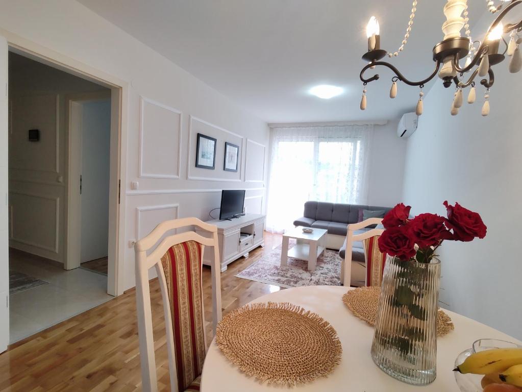 una sala de estar con una mesa con rosas en un jarrón en Apartment Allure, en Čapljina