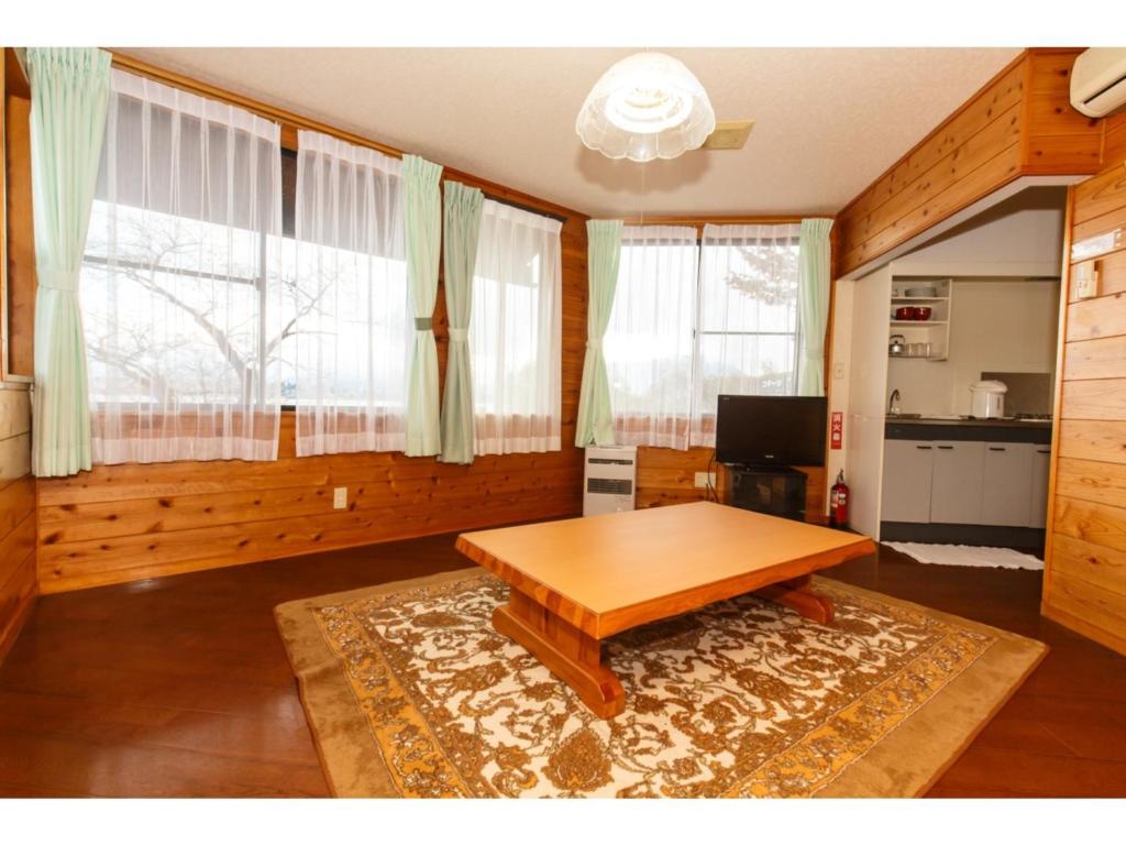 a living room with a wooden table and two windows at Lake Kawaguchi Rental Villa Tozawa Center - Vacation STAY 46658v in Oishi