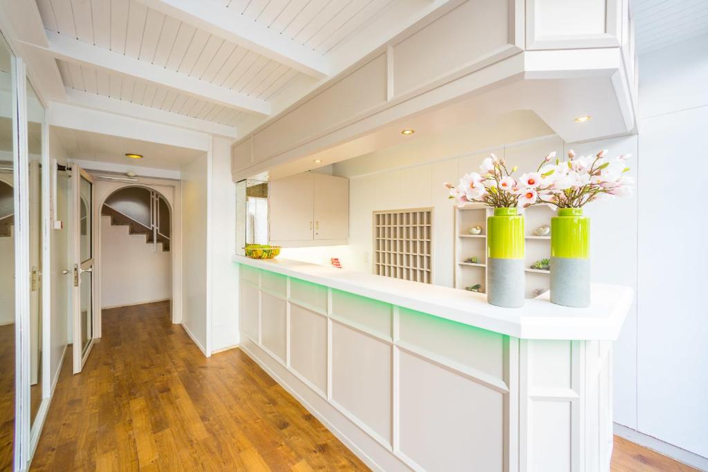 a kitchen with white cabinets and two vases with flowers at Hotel S16 in Munich