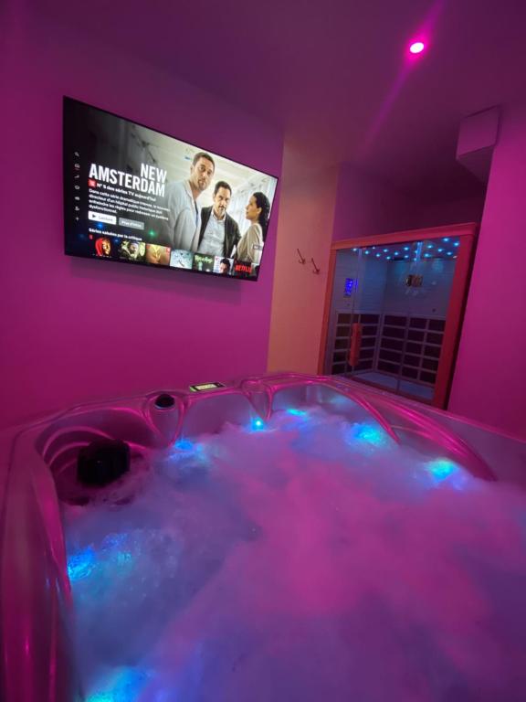 a room with a tub with a tv on the wall at Eaux Spa in Rouen