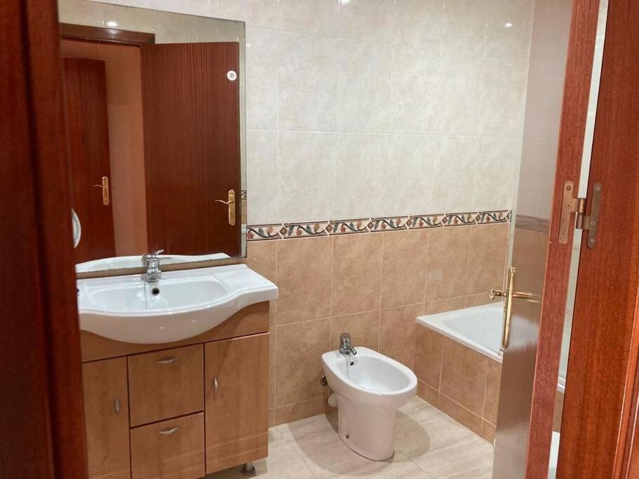 a bathroom with a sink and a toilet and a mirror at Piso vacacional en Sant Carles de la Ràpita. in Sant Carles de la Ràpita