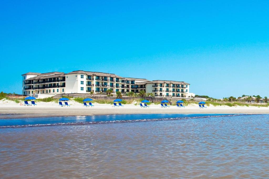 un grupo de personas sentadas en la playa con sombrillas en The Westin Jekyll Island Beach Resort en Jekyll Island