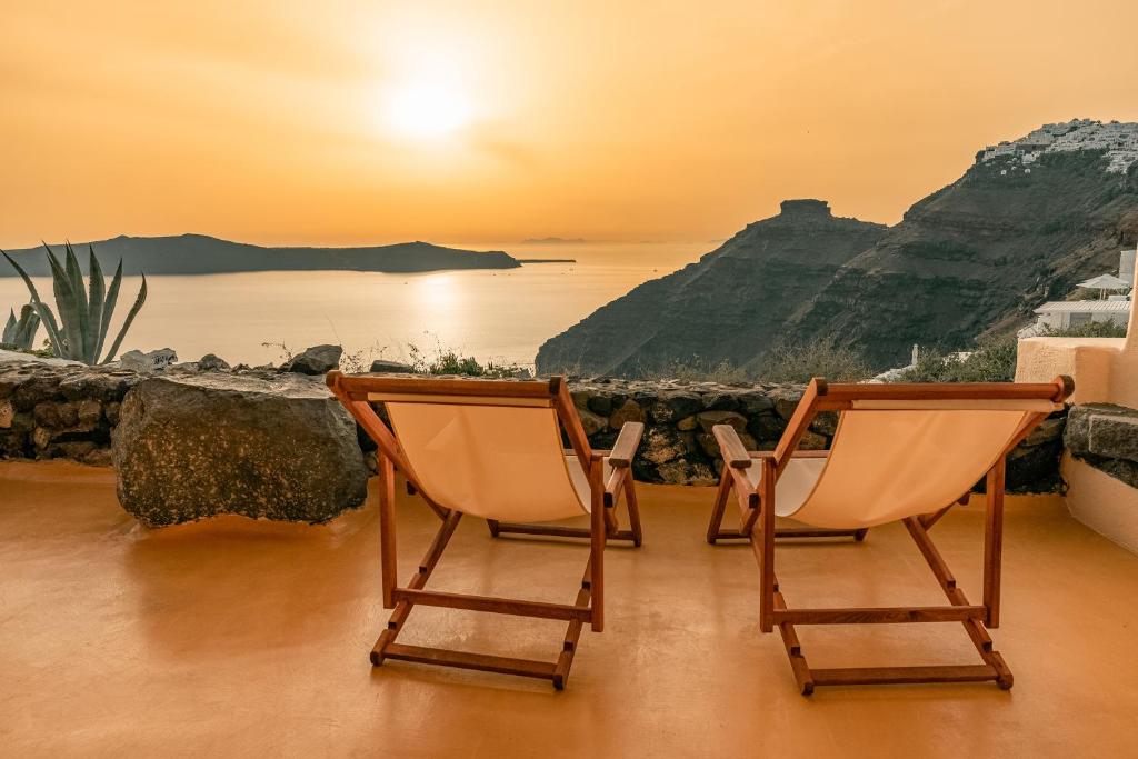 Duas cadeiras sentadas numa varanda com vista para o oceano em Sensyo Traditional Caves em Firostefani