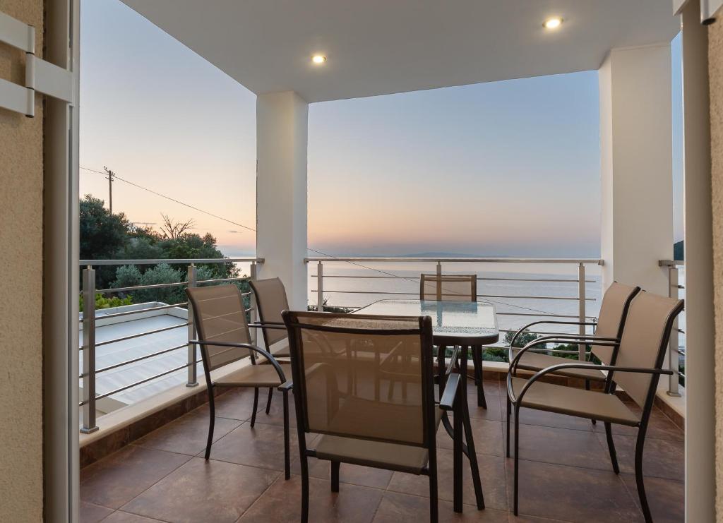 a balcony with a table and chairs and a view of the ocean at Nikole's Villas Cozy 80m2 in Tiros