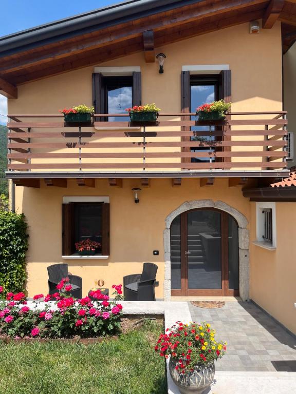a house with a balcony with flowers in the yard at Casa Conchet in Polcenigo