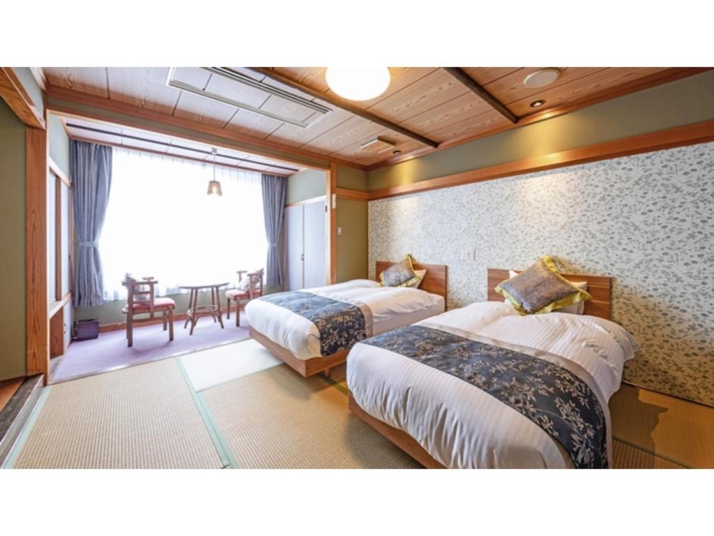 新発田市にあるTsukioka Onsen Furinya - Vacation STAY 55991vのベッド2台とダイニングルームが備わるホテルルームです。