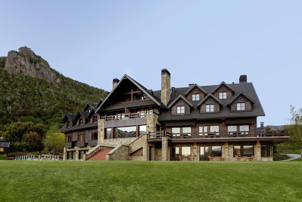 une grande maison en bois avec une montagne en arrière-plan dans l'établissement Arelauquen Lodge, a Tribute Portfolio Hotel, à San Carlos de Bariloche