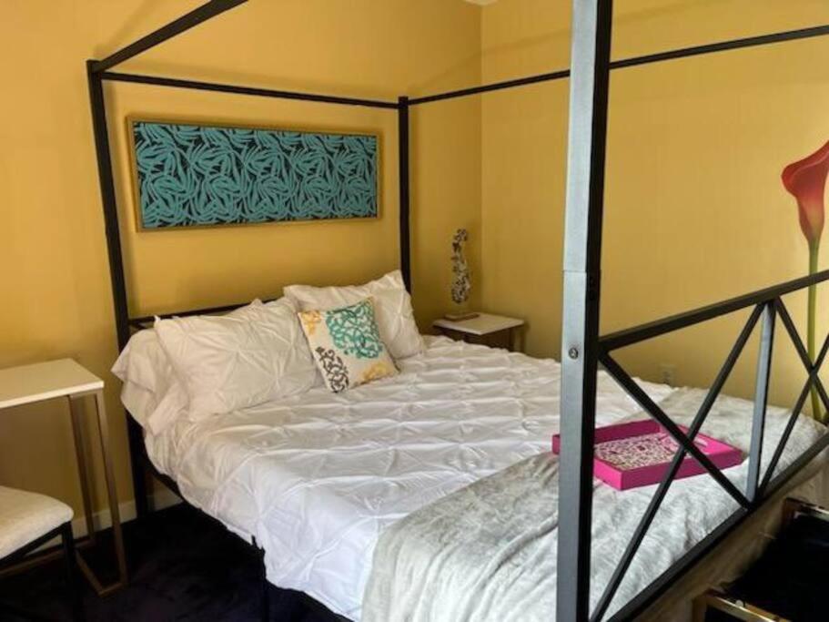 um quarto com uma cama branca com uma estrutura de metal em A Bliss of Color Townhouse em Jackson