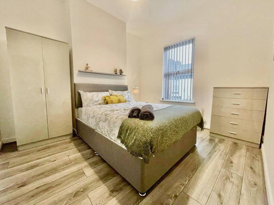 a bedroom with a bed with a dresser and a window at Brand New 2-BR Home Close to the City Centre in Liverpool