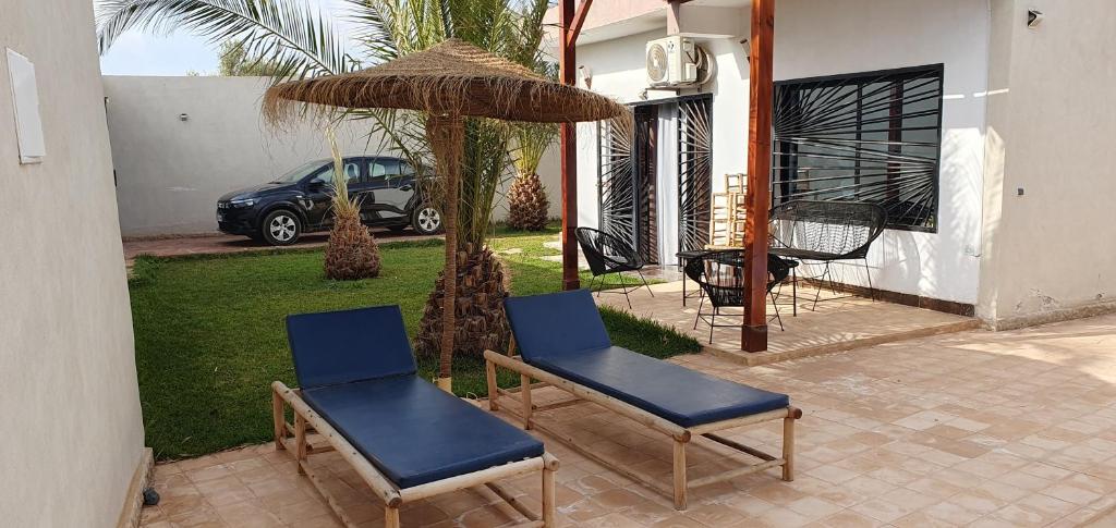 Villa avec piscine marrakech في مراكش: كرسيين ومظلة في ساحة