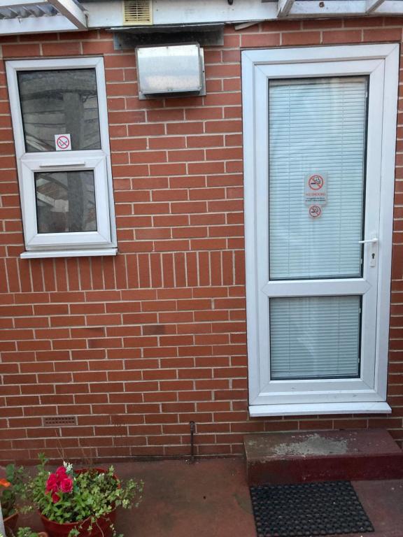 ceglany dom z dwoma oknami i drzwiami w obiekcie Harman Suites Self-Catering Apartments Free WIFI & Parking w mieście Leeds