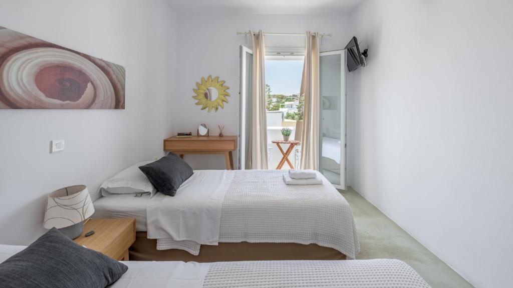 a white bedroom with a bed and a window at Litsa Malli Rooms in Pollonia