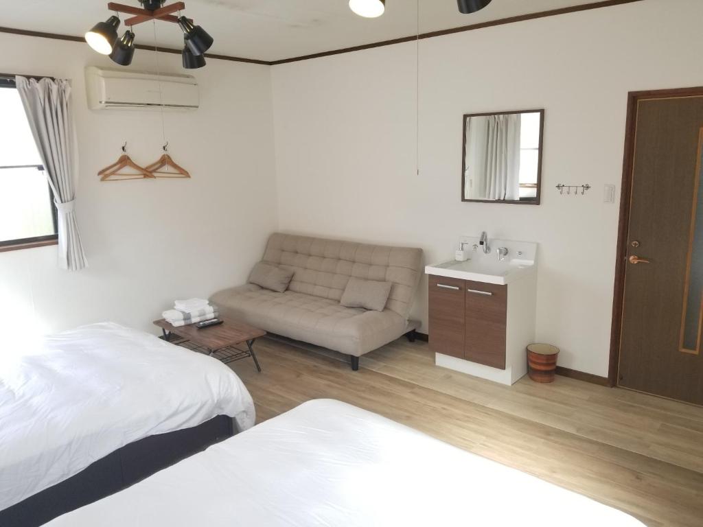 Guest House Tatara - Vacation STAY 61943v في Yasugi: غرفة نوم بسرير واريكة ومغسلة