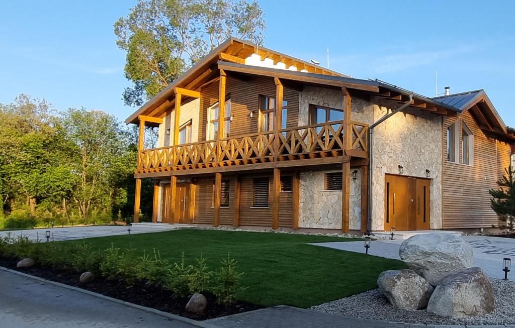 una gran casa de madera con césped delante en TatraTravel VILA unlimited golf for 2 person incl, en Veľká Lomnica