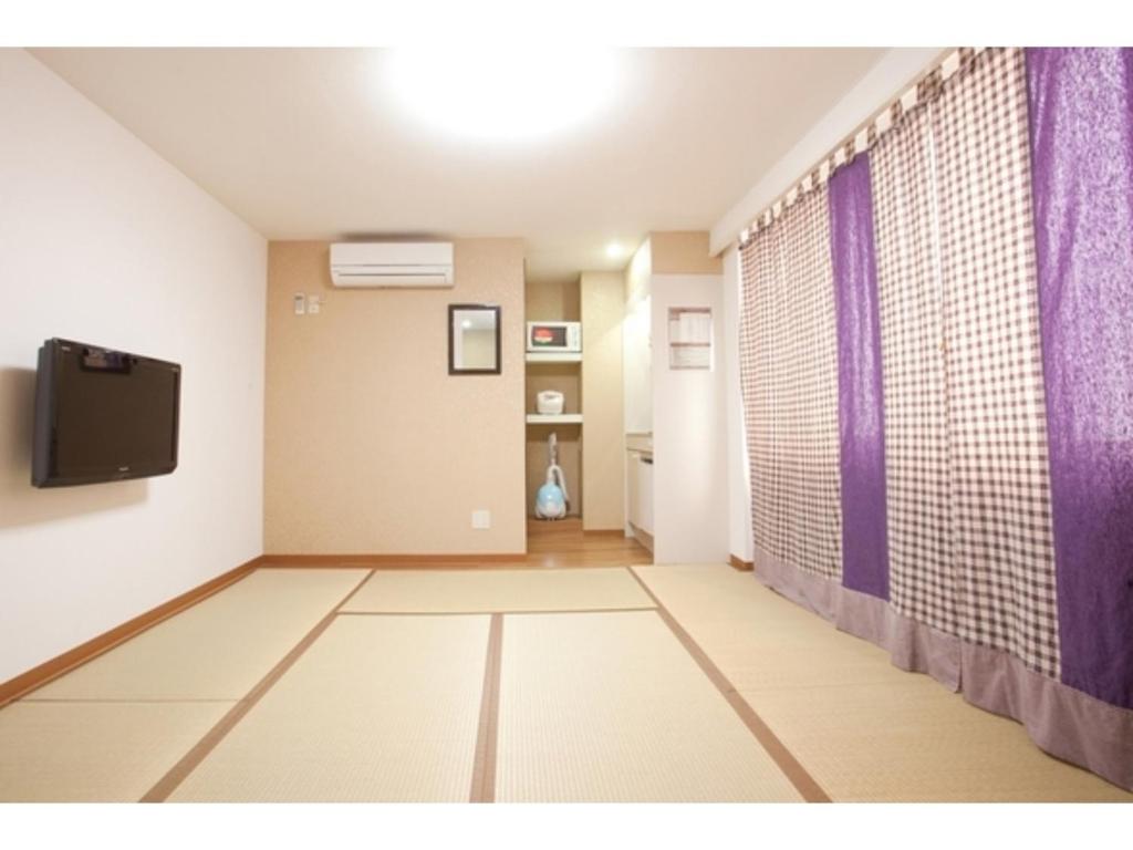 Habitación vacía con TV y cortinas moradas. en Hotel Hanabi - Vacation STAY 67139v, en Tokio