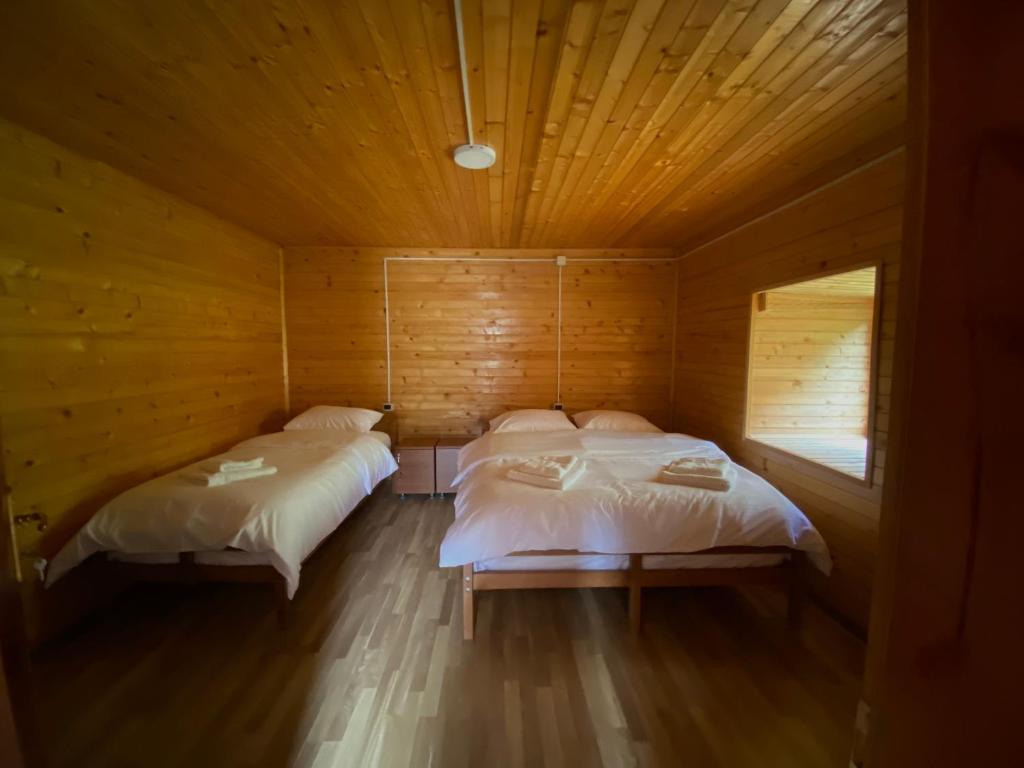 Habitación con 2 camas en una cabaña de madera en Guesthouse Rexhepi, en Kolgecaj