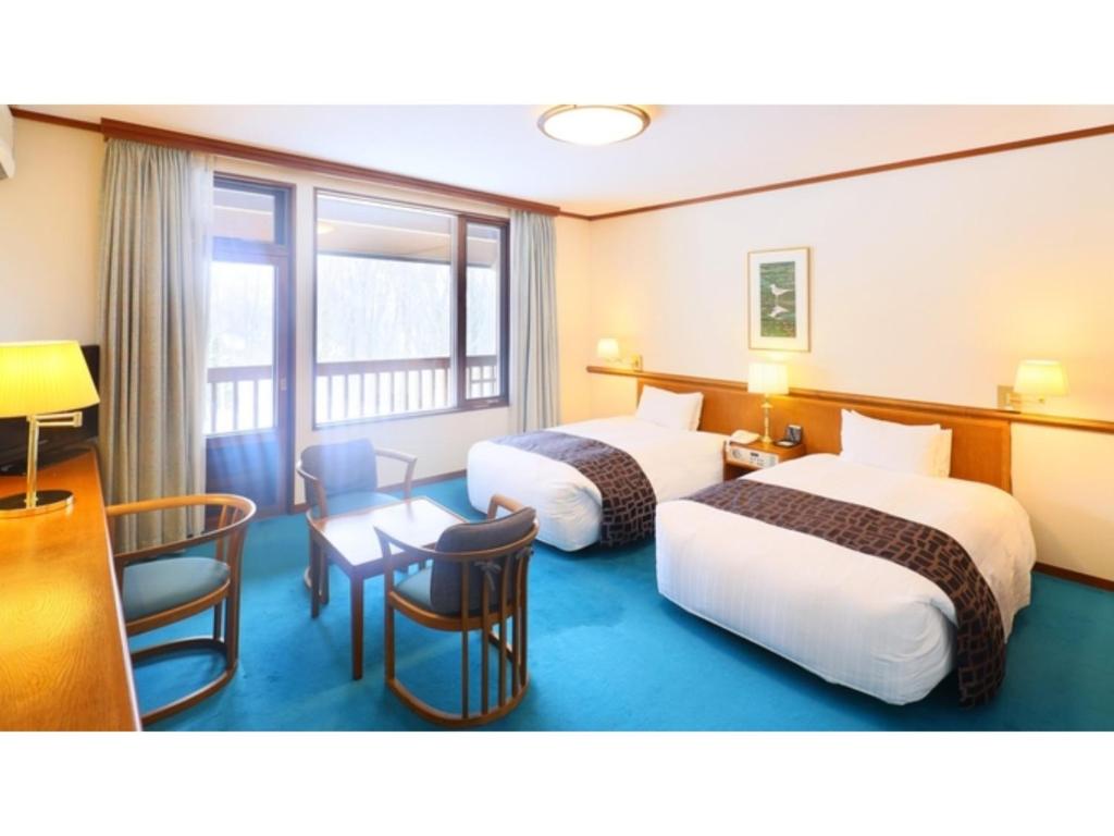 a hotel room with two beds and a table and chairs at Sukayu Onsen Hakkoda Hotel - Vacation STAY 66846v in Aomori