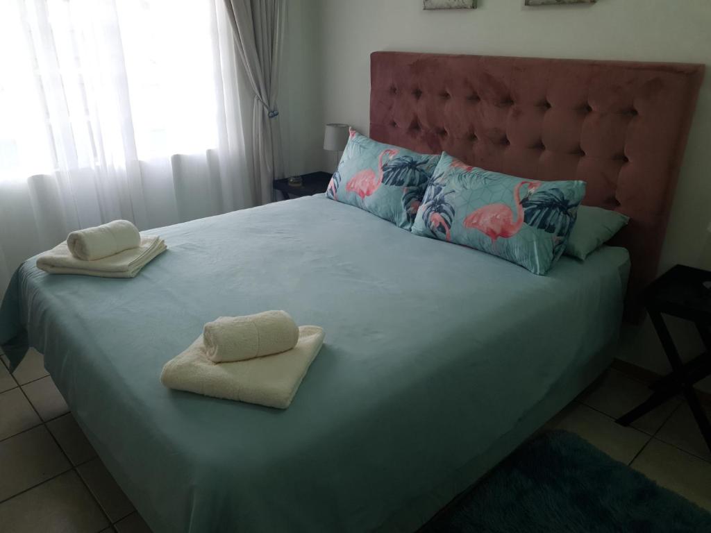 a bedroom with a large bed with two towels on it at Tia's Place in Krugersdorp