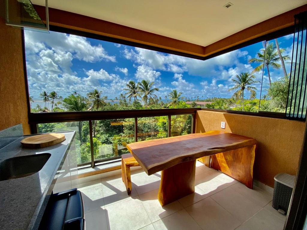 uma cozinha com um banco de madeira e uma grande janela em Flat luxo 04 torre 06 Eco Resort Carneiros em Tamandaré